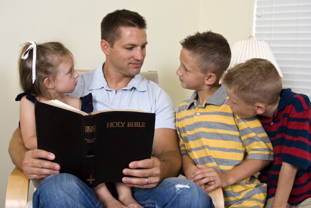 Dad and kids reading the Bible