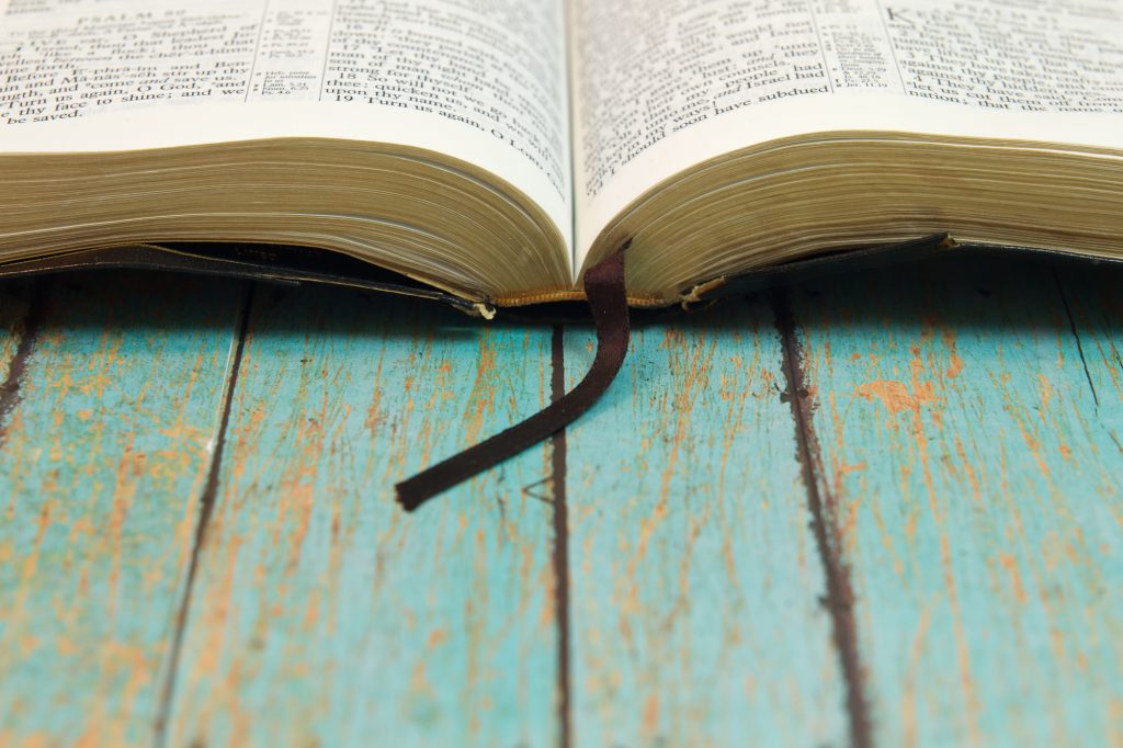 Open bible on wooden table with worn blue paint