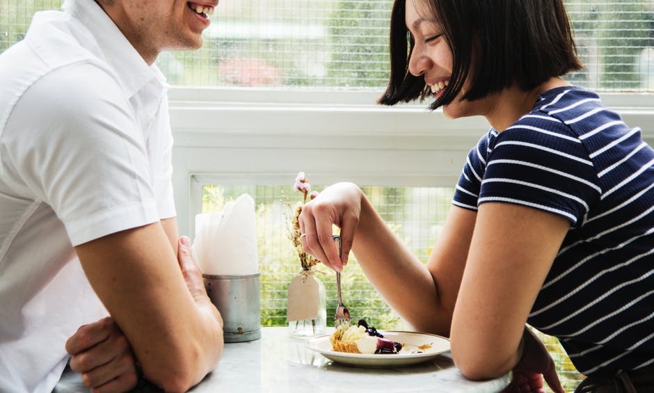 Man and woman laughing end eating dessert