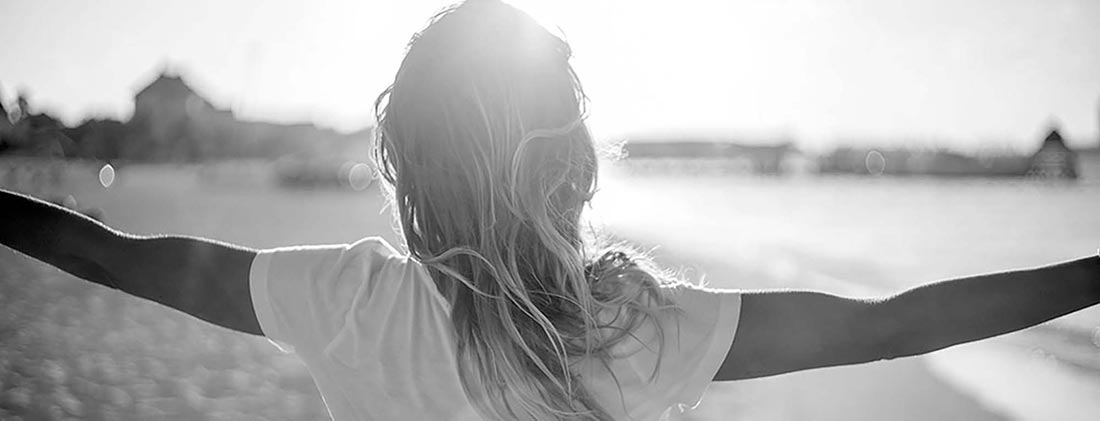 Person with arms stretched out facing sunrise