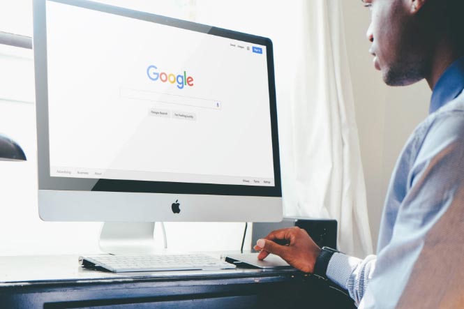 Person on computer using Google for search engine assist